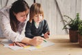 Mother teaching toddler boy to draw with pencils at home