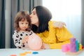 Mom Kissing Toddler Daughter Teaching her Financial Education