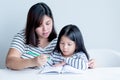 mother is teaching a 6 year old daughter to learn to write and read On white table Royalty Free Stock Photo