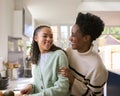 Mother With Teenage Daughter Helping To Prepare Meal At Home In Kitchen Together Royalty Free Stock Photo