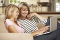 Mother With Teenage Daughter Sitting On Sofa At Home Using Laptop Royalty Free Stock Photo