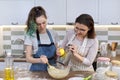 Mother and teenager daughter cook together at home in kitchen