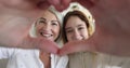 Mother and teenager daughter making heart sign with joined fingers