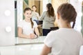 Mother and teenager girl preparing for photoshooting in dressing room in front of mirror