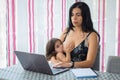 Mother teleworking in the dining room while breastfeeding Royalty Free Stock Photo