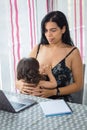Mother teleworking in the dining room while breastfeeding Royalty Free Stock Photo