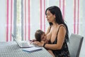 Mother teleworking in the dining room while breastfeeding Royalty Free Stock Photo