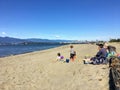 A mother and three children at the beach playing in the sand on a beautiful sunny day along Spanish Banks