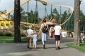 Mother with three children goes to an amusement park. Back view. Family goes to riding the roller coaster Royalty Free Stock Photo