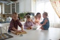 Mother with three children in the kitchen preparing cookies