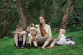 Mother and three children in park in clearing. Family picnic outdoors Royalty Free Stock Photo