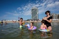 Mother and three children playing in the water on the beach in the summer Royalty Free Stock Photo