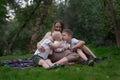 Mother and three children sitting on picnic blanket in park. Happy friendly family. Two brothers hug little sister Royalty Free Stock Photo