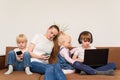 Mother and three children sitting on sofa each with own gadget. Problem of modern generation concept