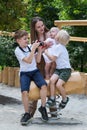 Mother and three children walk in the Park. Children ride on swing. Vertical frame Royalty Free Stock Photo