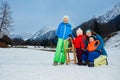 Mother and three kids play outside on snow slope with sledge