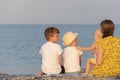 Mother and three small children sitting on the beach on sea background. Summer vacation with family Royalty Free Stock Photo