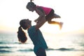 Mother throwing child up in her air at sunset on the beach