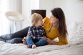 Mother toddler child and puppy dog lying on the bed reading book together family time