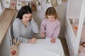 Mother, toddler child writing Christmas letter, advent calendar task