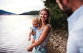 A mother with a toddler daughter outdoors by the river in summer.