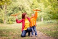 Mother and toddler son launching toy aircrafts in autumn park. Mom is kneeling, embracing her child. Dreams and travel concept Royalty Free Stock Photo