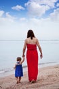 Mother with toddler walking on sand beach