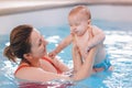 Mother traning her newborn baby to float in swimming pool