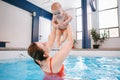 Mother traning her newborn baby to float in swimming pool