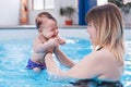 Mother traning her newborn baby to float in swimming pool