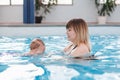 Mother traning her newborn baby to float in swimming pool