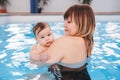 Mother traning her newborn baby to float in swimming pool