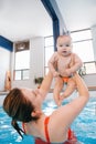 Mother traning her newborn baby to float in swimming pool