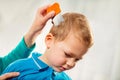 Mother treating son's hair against lice