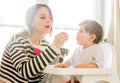 Mother try to feeding a toddler boy with a spoon in a chair Royalty Free Stock Photo