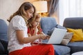 Mother assisting daughter with online lessons using laptop computer