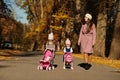 Mother and two baby daughters with stroller walking on autumn park Royalty Free Stock Photo