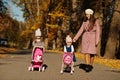 Mother and two baby daughters with stroller walking on autumn park Royalty Free Stock Photo