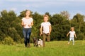 Mother with two boys and two dogs runs over a meadow Royalty Free Stock Photo