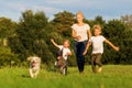 Mother with two boys and two dogs runs over a meadow Royalty Free Stock Photo