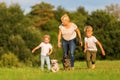 Mother with two boys and two dogs runs over a meadow Royalty Free Stock Photo