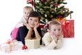 Mother and two children lying under Christmas tree with presents Royalty Free Stock Photo