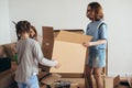 Mother two children at new home with cardboard boxes.