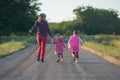 Mother and two children are running along the road countryside. Happy family