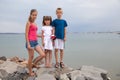 Mother and two children son and daughter standing together on big boulders on sea shore Royalty Free Stock Photo