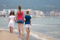 Mother and two children son and daughter walking together on sand beach in sea water in summer with bare feet in warm ocean waves Royalty Free Stock Photo