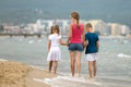 Mother and two children son and daughter walking together on sand beach in sea water in summer with bare feet in warm ocean waves Royalty Free Stock Photo