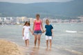 Mother and two children son and daughter walking together on sand beach in sea water in summer with bare feet in warm ocean waves Royalty Free Stock Photo