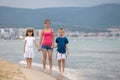 Mother and two children son and daughter walking together on sand beach in sea water in summer with bare feet in warm ocean waves Royalty Free Stock Photo