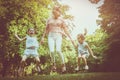 Mother with two daughter holding hands and jumping together. Royalty Free Stock Photo